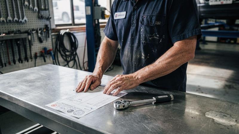 Certified technician reviewing a stamped repair record on a workbench